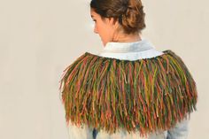 a woman wearing a jacket with multicolored fringes on it's back