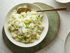 a white bowl filled with mashed potatoes on top of a wooden tray next to two plates