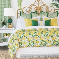 a bed with yellow and green pillows on top of it next to a white dresser