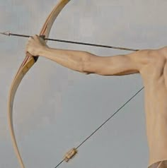 a man with no shirt is holding a bow and arrow