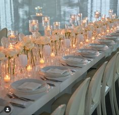 a long table is set with white flowers and candles for an elegant dinner or reception