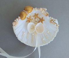 shells, pearls and seashells are attached to a white ribbon on a gray background