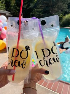 two drinks in plastic bags with straws on top and people swimming in the pool behind them