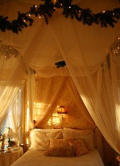 a canopy bed with white curtains and lights