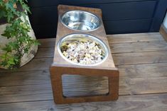 a wooden stand with two metal bowls on it