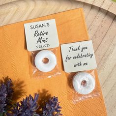 two donuts are sitting on top of a napkin and some purple flowers is in front of them