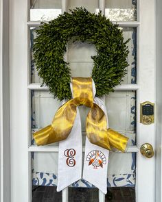 a white door with a yellow ribbon and a green wreath on the front door handle