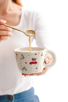 a woman holding a coffee cup with a spoon in it