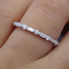 a woman's hand with a wedding ring on it, showing the side stones