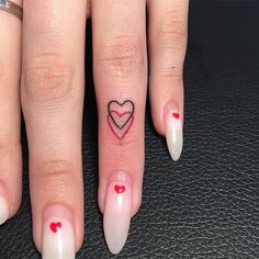 a woman's finger with a heart tattoo on it