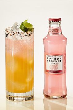 a bottle of london dry gin next to a tall glass filled with ice and lime