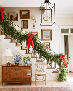 a staircase decorated for christmas with red bows and greenery on the bannisters