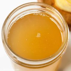 a glass jar filled with liquid next to an apple