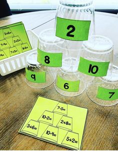 several cups with numbered numbers on them sitting on a wooden table next to a plastic container