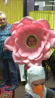 a young child is holding up a giant paper flower in the shape of a head