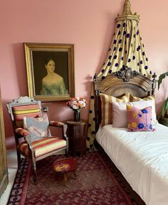 a bedroom with a bed, chair and paintings on the wall in it's corner