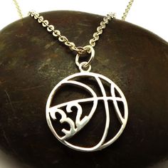 a silver basketball necklace on a rock