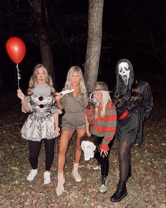 three women dressed up in halloween costumes posing for a photo with one holding a red balloon