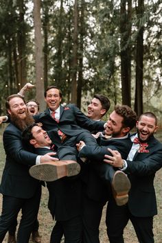 a group of men standing next to each other in front of some trees and grass