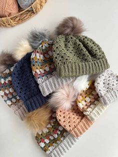 several knitted hats with pom - poms in different colors and sizes on top of each other