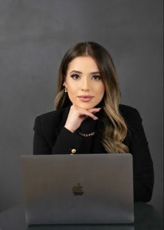 a woman sitting at a table with a laptop in front of her, looking to the side