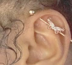 a close up of a person's ear with piercings on it and a cross behind the ear