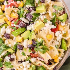 a bowl filled with pasta salad topped with avocado, corn and feta cheese