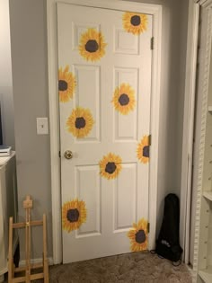 a white door with sunflowers painted on it and a black bag next to it