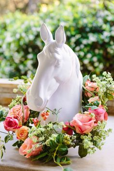 a white horse head surrounded by flowers and greenery