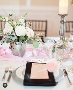 the table is set with white flowers and silverware