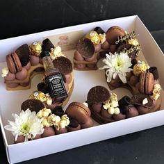 a box filled with donuts covered in chocolate frosting and topped with edible flowers