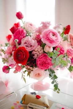 a vase filled with lots of pink and red flowers