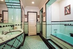 this bathroom has green and black tile on the walls, along with a bathtub