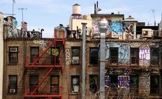 an old brick building with graffiti on the windows and balconies, next to a fire escape