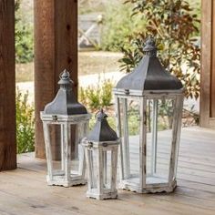 two white lanterns sitting on top of a wooden deck