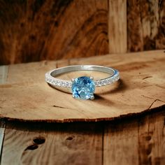 This Blue Topaz Ring features a slender band with a 6mm natural Blue Topaz gemstone. The band is also embellished with moissanite stones, adding an extra touch of elegance and luxury., Why this Topaz Ring:   - Slim and Elegant Design. Beautiful Color of the Stone. - Topaz is a gemstone that symbolizes love, affection, and good fortune. It is believed to bring warmth and energy to the wearer, fostering joy and contentment. - Handmade from Solid S925 Silver and natural gemstone. - As a December bi Luxury Blue Topaz Birthstone Ring, Topaz Crystal Ring With Center Stone, Topaz Diamond Ring With Accent Stones For Promise, Blue Topaz Ring With Accent Stones, Round Cut, Light Blue Sapphire Ring With Center Stone, Aquamarine Crystal Promise Ring With Center Stone, Topaz Birthstone Ring For Promise, Topaz Rings With Accent Stones For Promise, Blue Topaz Birthstone Ring For Promise