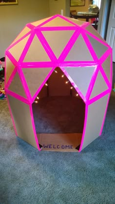 a pink and grey ball shaped like a house with lights on the inside, sitting in a living room next to a door