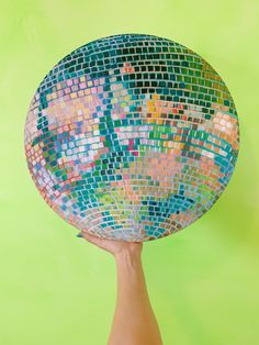 a person's hand holding up a disco ball shaped like a map of the world