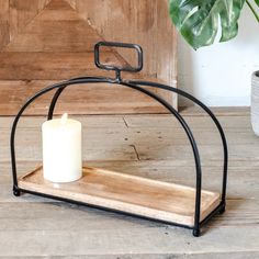 a candle sits on a wooden tray with a metal frame and holds a white candle