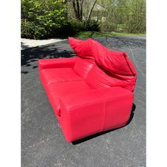 a red couch sitting on top of a parking lot