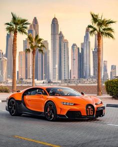 an orange bugatti parked in front of a cityscape with palm trees