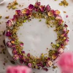 a cake with flowers on it sitting on top of a white plate next to pink roses