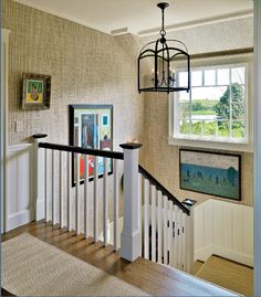 a staircase with pictures on the wall and paintings on the wall behind it, along with a chandelier