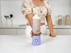 a woman holding a blender filled with whipped cream