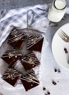 chocolate brownies with white and gold sprinkles are on a plate next to a glass of milk