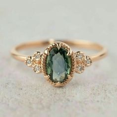 a ring with an oval shaped green stone surrounded by small white and brown diamonds on top