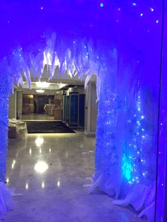 an archway decorated with blue lights and frosted trees in the middle of a room