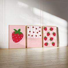 three canvases with strawberries on them sitting in front of a white wall and wooden floor