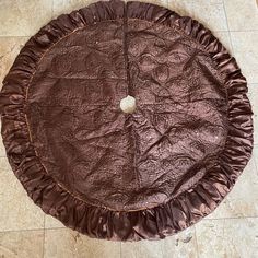 a round brown table with ruffles on the edges and a white ball in the center