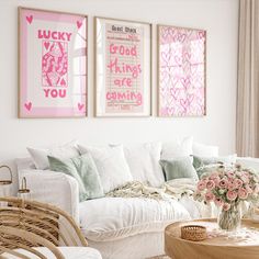 a living room filled with white furniture and pink art on the wall above it's coffee table